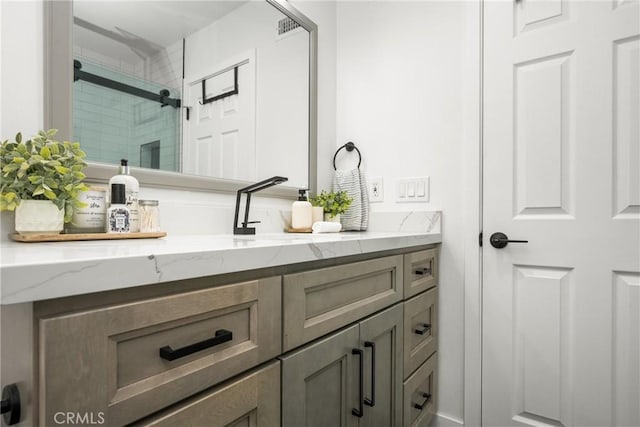 bathroom featuring a shower with door and vanity