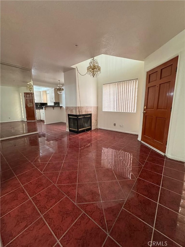 unfurnished living room featuring an inviting chandelier, a fireplace, and dark tile patterned flooring