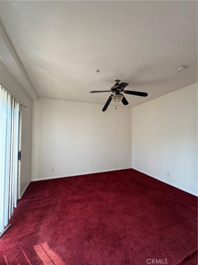 empty room featuring ceiling fan, dark carpet, and a textured ceiling