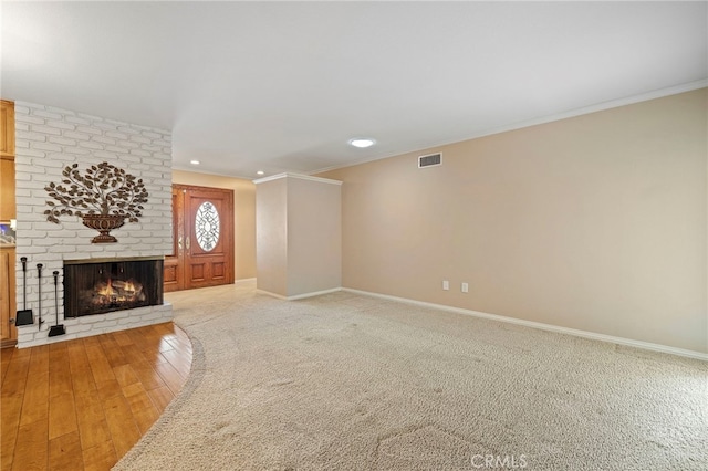 unfurnished living room with ornamental molding, carpet, and a brick fireplace