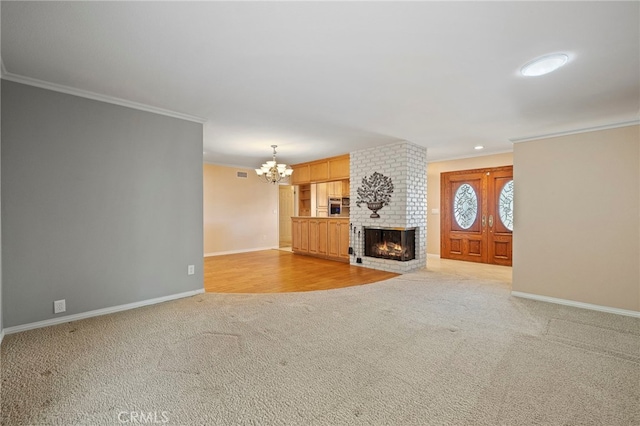 unfurnished living room with light carpet, a brick fireplace, crown molding, and a chandelier