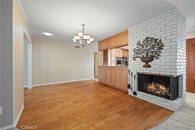 unfurnished living room featuring crown molding, a brick fireplace, a notable chandelier, and light wood-type flooring