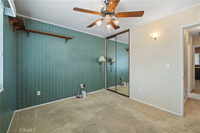 unfurnished bedroom with crown molding, carpet floors, a closet, and ceiling fan