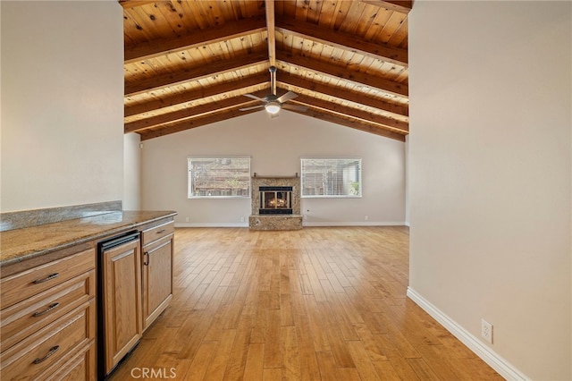 unfurnished living room featuring a fireplace, lofted ceiling with beams, ceiling fan, light hardwood / wood-style floors, and wood ceiling