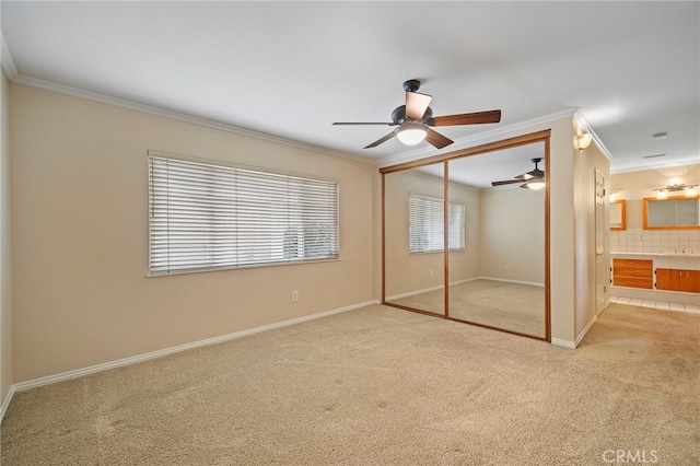 unfurnished bedroom featuring connected bathroom, ornamental molding, ceiling fan, light carpet, and a closet