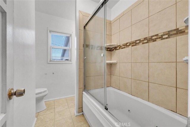 bathroom with toilet, tile patterned flooring, and combined bath / shower with glass door