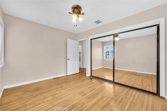 unfurnished bedroom featuring light hardwood / wood-style floors, a closet, and ceiling fan