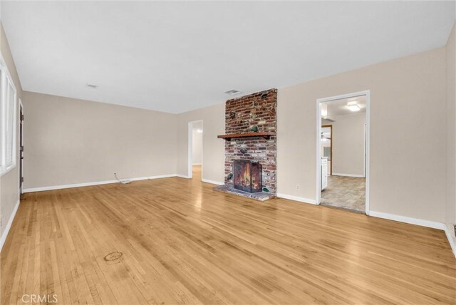 unfurnished living room featuring a brick fireplace and light hardwood / wood-style flooring