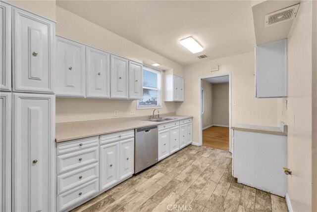 kitchen featuring dishwasher, sink, white cabinets, and light wood-type flooring