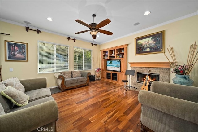 living room featuring ornamental molding, hardwood / wood-style floors, ceiling fan, and a high end fireplace