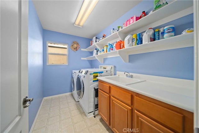 clothes washing area featuring cabinets, sink, and washing machine and dryer