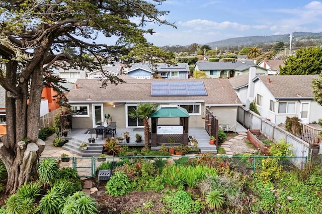 rear view of house featuring a deck with mountain view and solar panels