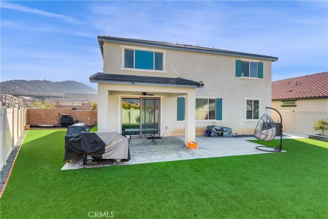 back of property with a mountain view, a yard, a patio, and ceiling fan