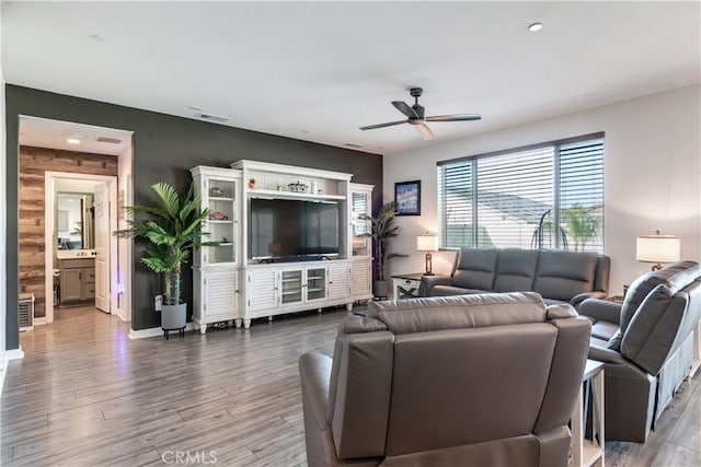 living room with ceiling fan, hardwood / wood-style floors, and wood walls