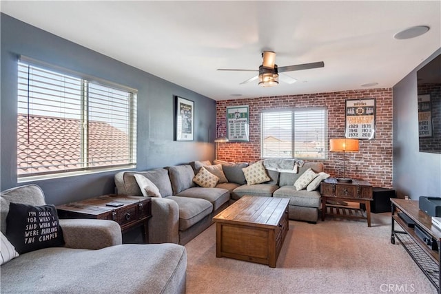 carpeted living room featuring brick wall, plenty of natural light, and ceiling fan