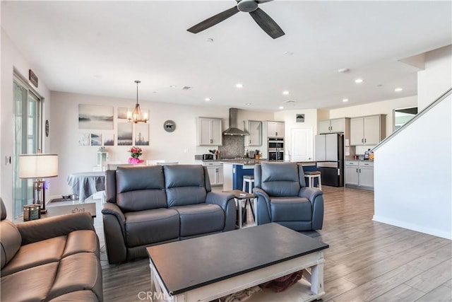 living room with ceiling fan with notable chandelier and wood-type flooring