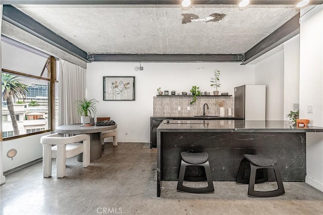 interior space featuring sink, stainless steel refrigerator, and a breakfast bar