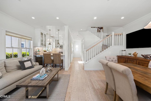 living room featuring ornamental molding, sink, and light hardwood / wood-style flooring