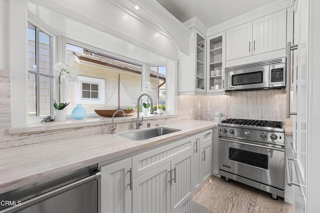 kitchen with sink, stainless steel appliances, tasteful backsplash, light stone counters, and white cabinets
