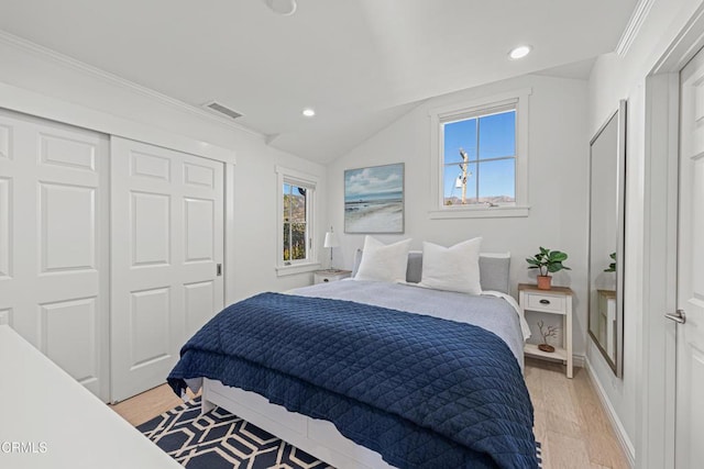 bedroom featuring a closet, lofted ceiling, light hardwood / wood-style flooring, and ornamental molding