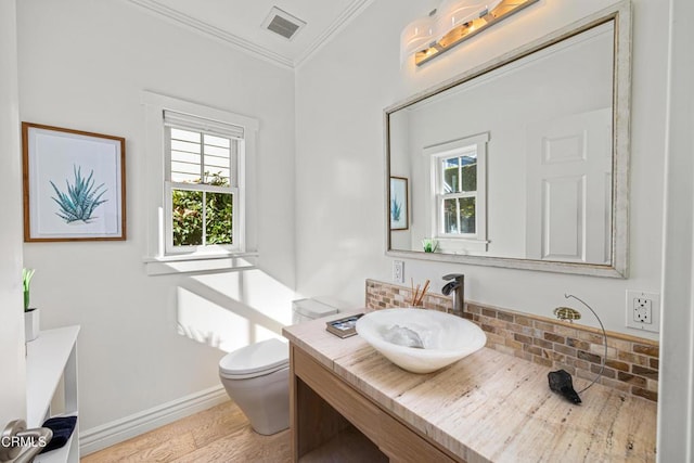 bathroom with hardwood / wood-style flooring, backsplash, vanity, ornamental molding, and toilet