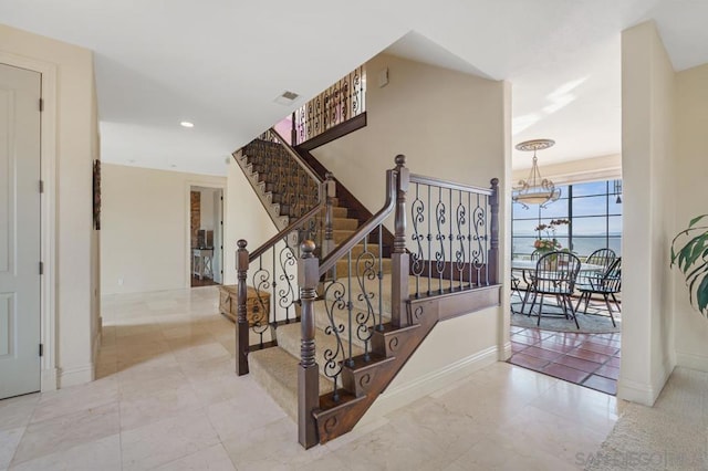 staircase with an inviting chandelier