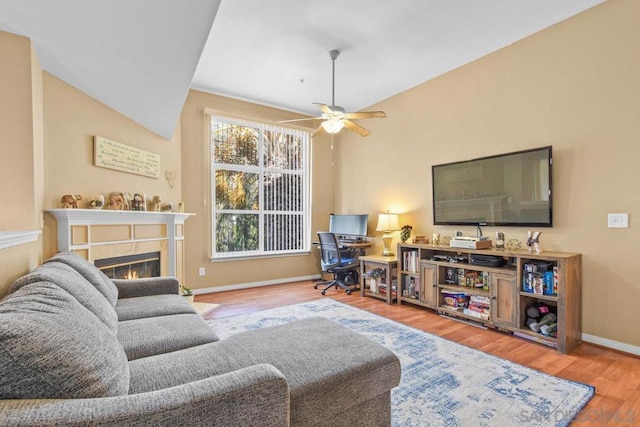 living room featuring ceiling fan, wood-type flooring, and a fireplace