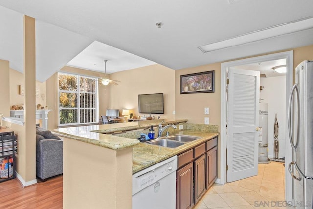 kitchen featuring sink, stainless steel refrigerator, dishwasher, light stone counters, and kitchen peninsula