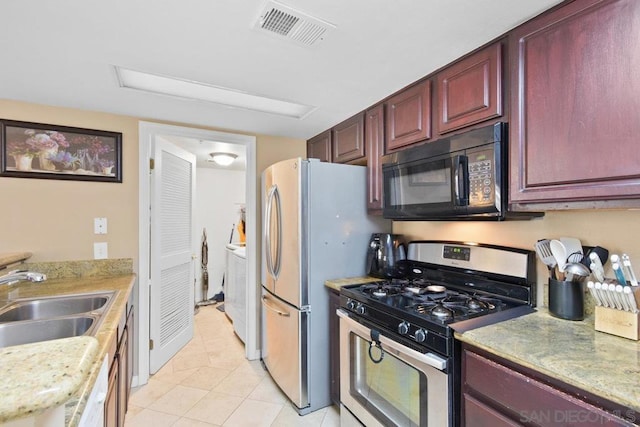 kitchen with stainless steel appliances, light tile patterned flooring, washer and dryer, and sink