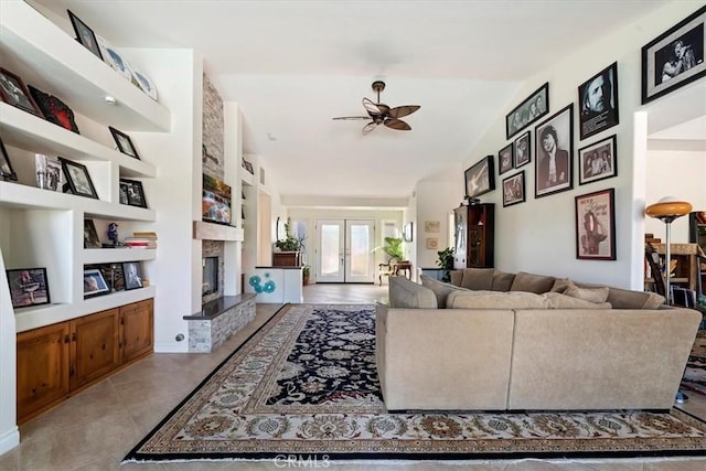 living room with ceiling fan, a high end fireplace, built in shelves, vaulted ceiling, and french doors