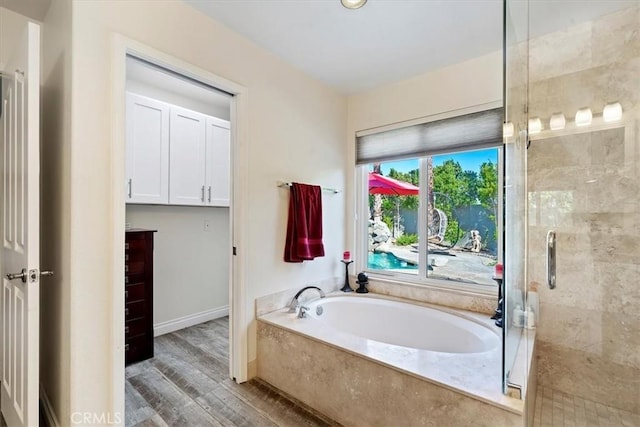 bathroom featuring wood-type flooring and shower with separate bathtub