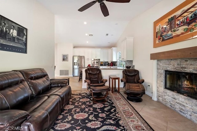 living room featuring ceiling fan, sink, light tile patterned floors, and a fireplace