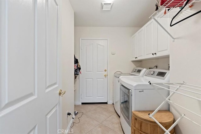 washroom featuring cabinets, washer and dryer, and light tile patterned floors