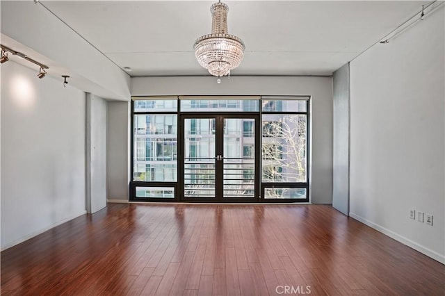 unfurnished room featuring an inviting chandelier and wood-type flooring