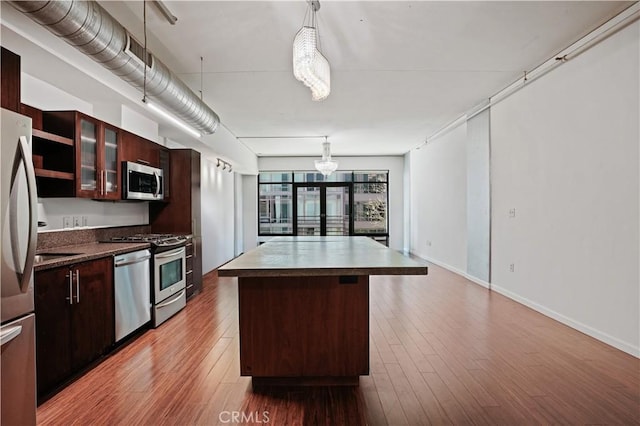 kitchen featuring hardwood / wood-style flooring, stainless steel appliances, hanging light fixtures, and a kitchen island