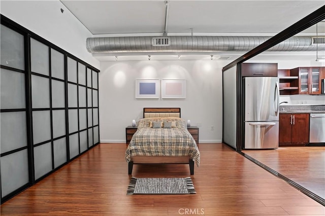 bedroom with hardwood / wood-style flooring, sink, and stainless steel fridge