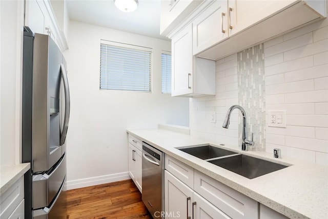 kitchen featuring sink, appliances with stainless steel finishes, white cabinetry, dark hardwood / wood-style floors, and light stone countertops