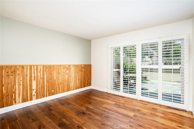 unfurnished room featuring wood-type flooring and wooden walls