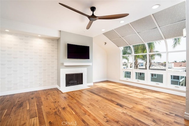 unfurnished living room with hardwood / wood-style flooring, ceiling fan, and a brick fireplace