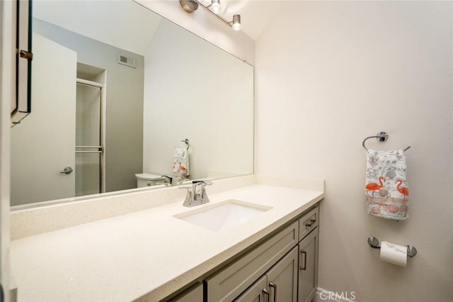 bathroom with walk in shower, vanity, and toilet