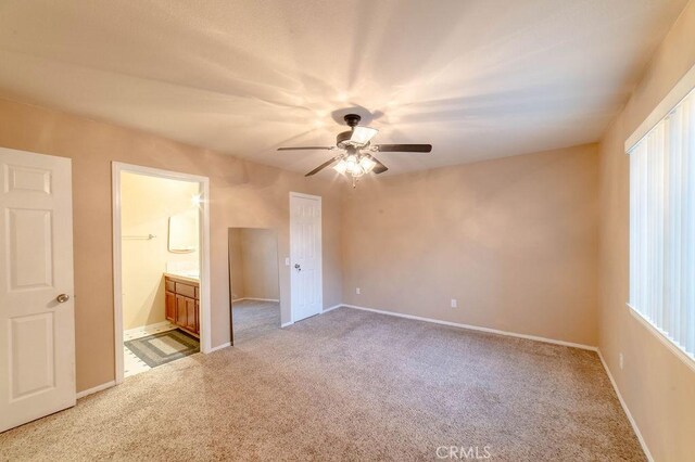 unfurnished bedroom featuring ceiling fan, ensuite bathroom, and carpet floors