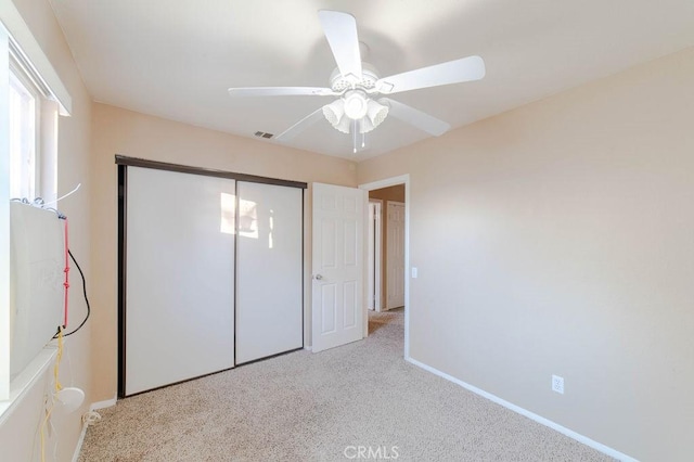 unfurnished bedroom featuring light carpet, a closet, and ceiling fan