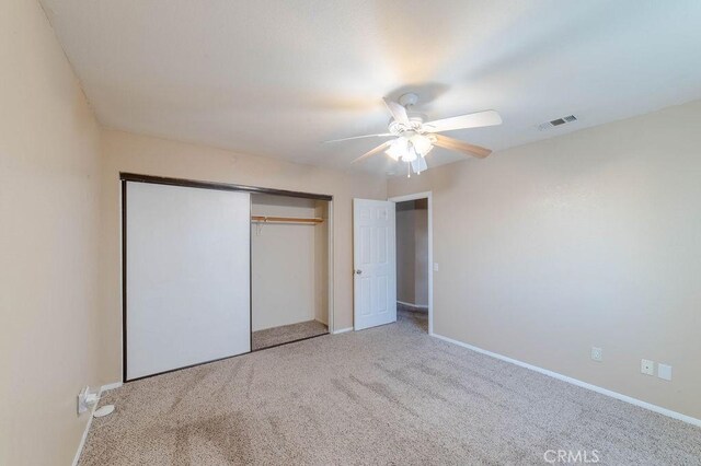 unfurnished bedroom with ceiling fan, carpet, and a closet