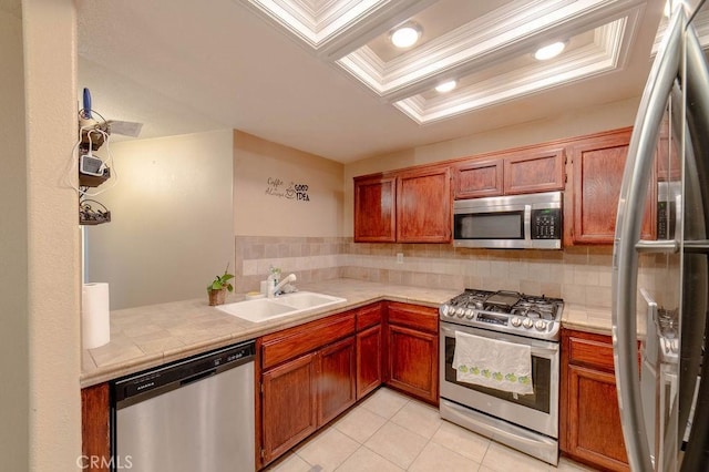 kitchen with sink, crown molding, backsplash, stainless steel appliances, and a tray ceiling