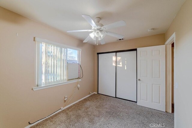 unfurnished bedroom featuring ceiling fan, light colored carpet, and a closet