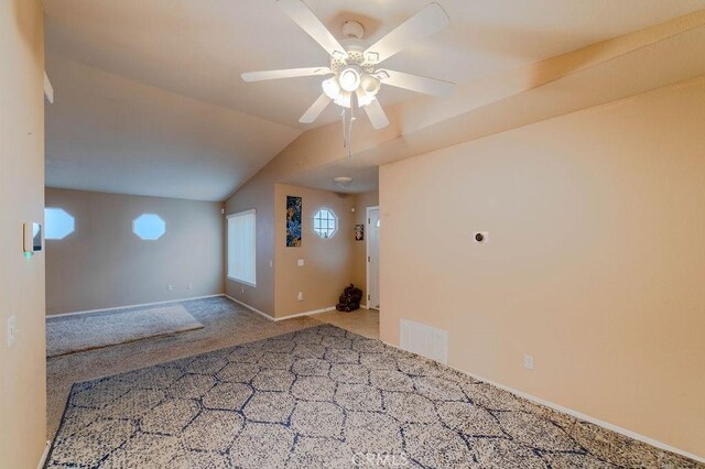 empty room with vaulted ceiling, carpet floors, and ceiling fan