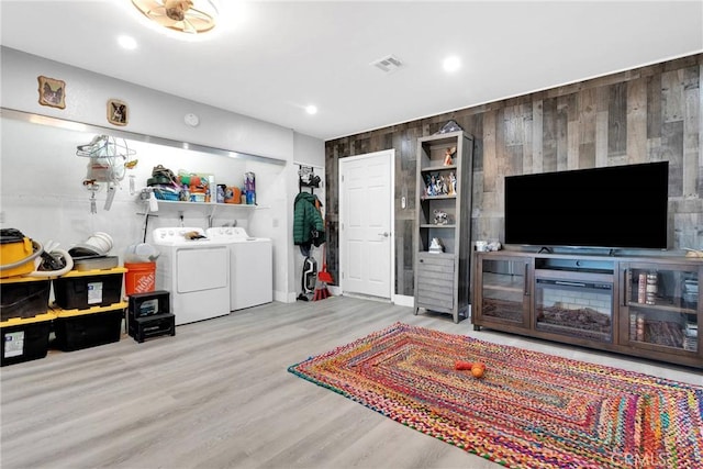 living room featuring wood walls, separate washer and dryer, and light wood-type flooring