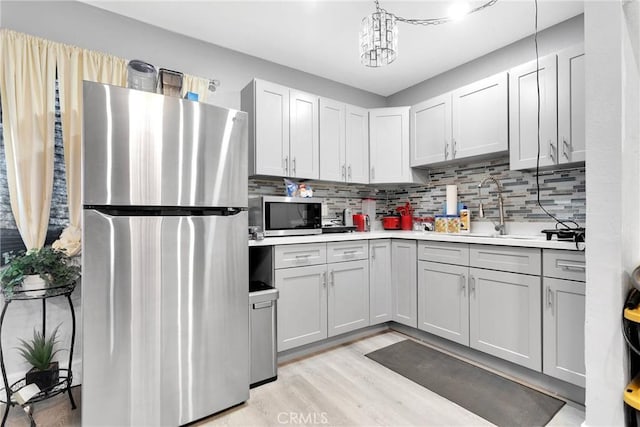 kitchen with pendant lighting, appliances with stainless steel finishes, sink, and backsplash