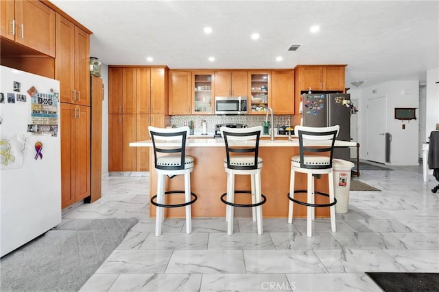 kitchen with an island with sink, appliances with stainless steel finishes, a kitchen bar, and decorative backsplash