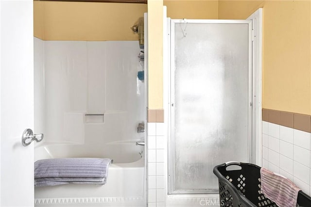 bathroom featuring plus walk in shower and tile walls